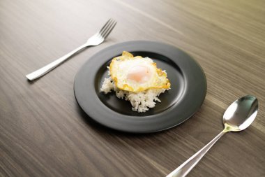 Kızarmış yumurta, siyah bir tabakta beyaz pirincin üzerine.