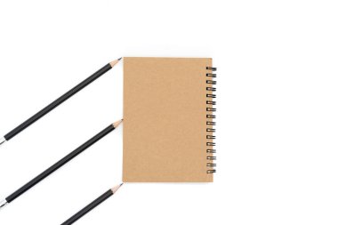 Bu kahverengi kitap resmin ortasına ve resmin sol tarafına çapraz ve beyaz arka planda üç siyah kalem yerleştirilir..