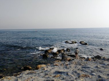 Hasır şapkalı bir kız dalgaların tadını çıkarıyor, deniz dalgalarına iniyor..