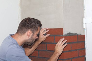 Evi yeniden inşası. İşçi tuğla kaplama (İmitasyon tuğla) dış cephe üzerinde sıkışmış. Yeni cephe üzerinde iş bitirme.