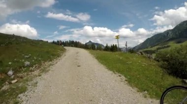 Avusturya Alpleri'nde yaz saati. Bisiklet eteklerinde genç bir kadın. Güzel bisikletçi güzel manzara ile sürmek. Avusturya Alp Bisiklet Yolu. Stabilize video.