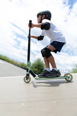 Küçük tatlı bir çocuk kaykay parkında scooter sürüyor. Genç bir acemi sporcu ekstrem sporlarda boş zaman geçirir. Yaşam biçimi.