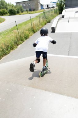 Küçük tatlı bir çocuk kaykay parkında scooter sürüyor. Genç bir acemi sporcu ekstrem sporlarda boş zaman geçirir. Yaşam biçimi.