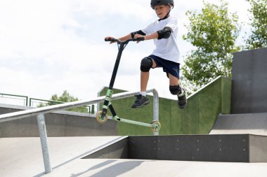 Düşerken zıpla. Küçük tatlı bir çocuk kaykay parkında scooter kullanıyor. Genç bir acemi sporcu ekstrem sporlarda boş zaman geçirir..