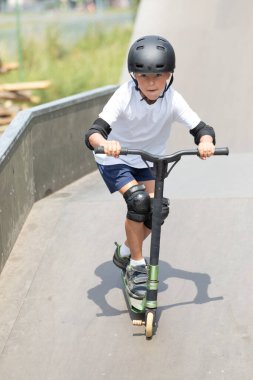 Küçük tatlı bir çocuk kaykay parkında scooter sürüyor. Genç bir acemi sporcu ekstrem sporlarda boş zaman geçirir. Yaşam biçimi.