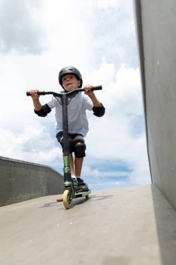 Küçük tatlı bir çocuk kaykay parkında scooter sürüyor. Genç bir acemi sporcu ekstrem sporlarda boş zaman geçirir. Yaşam biçimi.