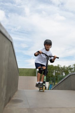 Küçük tatlı bir çocuk kaykay parkında scooter sürüyor. Genç bir acemi sporcu ekstrem sporlarda boş zaman geçirir. Yaşam biçimi.