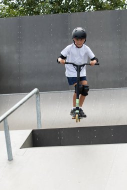 Küçük tatlı bir çocuk kaykay parkında scooter sürüyor. Genç bir acemi sporcu ekstrem sporlarda boş zaman geçirir. Yaşam biçimi.