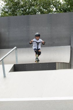 Küçük tatlı bir çocuk kaykay parkında scooter sürüyor. Genç bir acemi sporcu ekstrem sporlarda boş zaman geçirir. Yaşam biçimi.