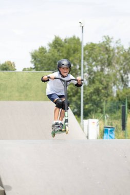Küçük tatlı bir çocuk kaykay parkında scooter sürüyor. Genç bir acemi sporcu ekstrem sporlarda boş zaman geçirir. Yaşam biçimi.