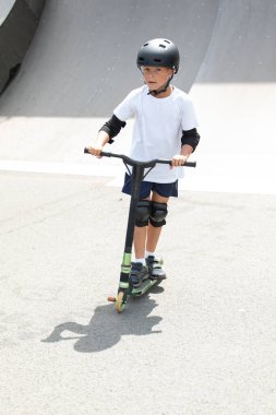 Küçük tatlı bir çocuk kaykay parkında scooter sürüyor. Genç bir acemi sporcu ekstrem sporlarda boş zaman geçirir. Yaşam biçimi.