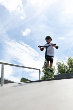 Küçük tatlı bir çocuk kaykay parkında scooter sürüyor. Genç bir acemi sporcu ekstrem sporlarda boş zaman geçirir. Yaşam biçimi.