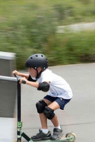 一个可爱的小男孩在一个滑板公园里骑摩托车 一个年轻的新手运动员在极限运动上花时间 可互换运动模糊的运动照片 — 图库照片