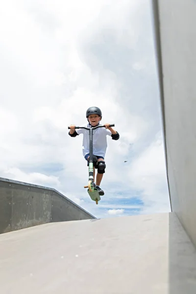 The boy jumps on a scooter
