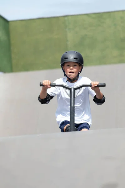 一个可爱的小男孩在一个滑板公园里骑摩托车 一个年轻的新手运动员在极限运动上花时间 生活方式 — 图库照片
