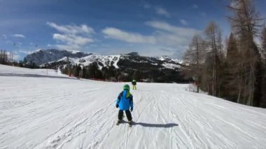 Küçük çocuk kayak yapıyor. 6 yaşındaki bir çocuk Alp tatil beldesinde kış tatilinin tadını çıkarıyor. Sabit görüntü. Yavaş çekim. 