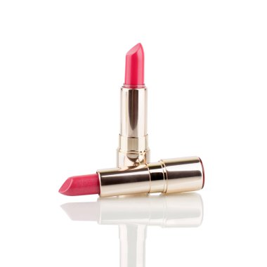 Beyaz arka planda iki kırmızı ve pembe ruj, cam yüzeyde ayna yansıması izole edilmiş yakın plan, parlak altın pakette açık ruj, lüks kozmetik aksesuar, stüdyo çekimi.