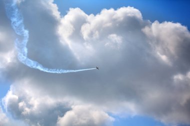 Mavi gökyüzünde bir uçak ve gökyüzünde büyük beyaz bir bulut.