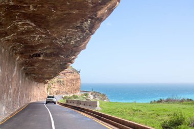Deniz kıyısı boyunca dağ yolu, turkuaz okyanus suyu deniz manzarası, mavi gökyüzü, masmavi deniz manzarası, Chapmans Peak Yolu, güzel dağ manzarası, Cape Town, Güney Afrika kıyı seyahati.