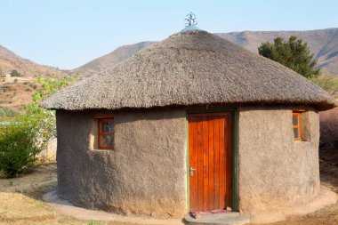 Geleneksel Afrikalı yuvarlak kil evler köyde sazdan çatı, Lesotho Krallığı, Güney Afrika, etnik bazotho halkı eski ulusal ev, Drakensberg dağları manzara arka planı