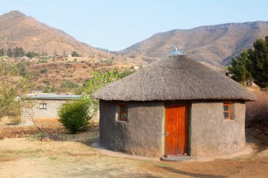 Geleneksel Afrikalı yuvarlak kil evler köyde sazdan çatı, Lesotho Krallığı, Güney Afrika, etnik bazotho halkı eski ulusal ev, Drakensberg dağları manzara arka planı