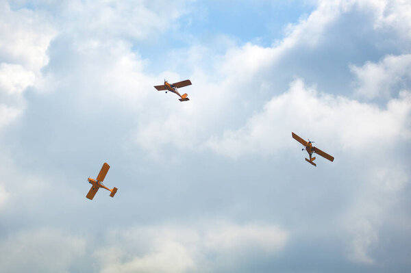 Novosibirsk, Russia, July 31, 2016, Mochishche airfield, local air show three yellow planes fly together on a blue sky and white clouds background, close up