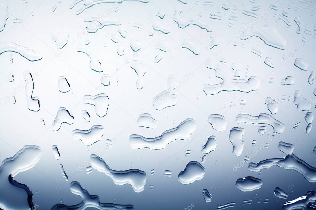 Drops of spilled water on mirror glass surface, water blots, abstract design background, wet textured gradient pattern in blue color, close up, top view