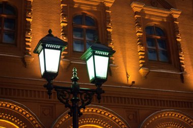 Rusya 'nın tarihi merkezinde, Moskova' nın gece ya da akşam kentinde, antik bir binanın demir direğinde parlayan bir fener.