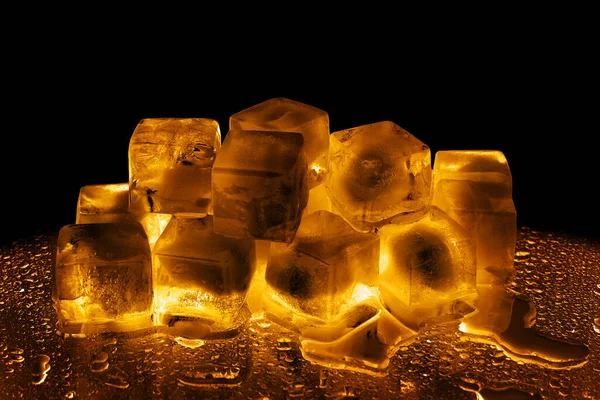 黒の背景に黄金の氷のキューブを隔離された閉鎖 透明な凍結融解琥珀色の水 黄色のバックライト 抽象的な冷たいアルコール飲料のコンセプト 夜のパーティーのデザイン コピースペース — ストック写真