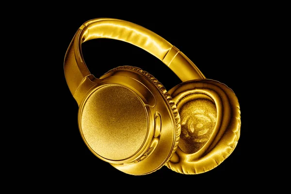 Golden shiny wireless headphones on black background isolated close up, luxury gold metal bluetooth headset, modern high end wi-fi yellow earphones, audio music symbol, stereo sound electronics sign