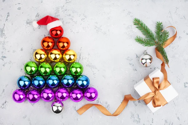 Christmas tree made of decorations glass balls LGBTQ community rainbow flag colors, Santa Claus hat, gift box, fir branch, LGBT pride symbol, New Year holidays greeting card design, text copy space