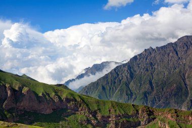 Mavi gökyüzündeki dağ sıraları ve dağlar ve beyaz büyük bulutlar yakın plan, Kafkas dağları, Kazbek dağı, Georgia