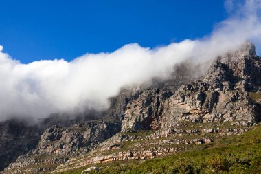Masa Dağı büyük beyaz bir bulutun altında, derin mavi gökyüzü arkaplanı, Cape Town, Güney Afrika