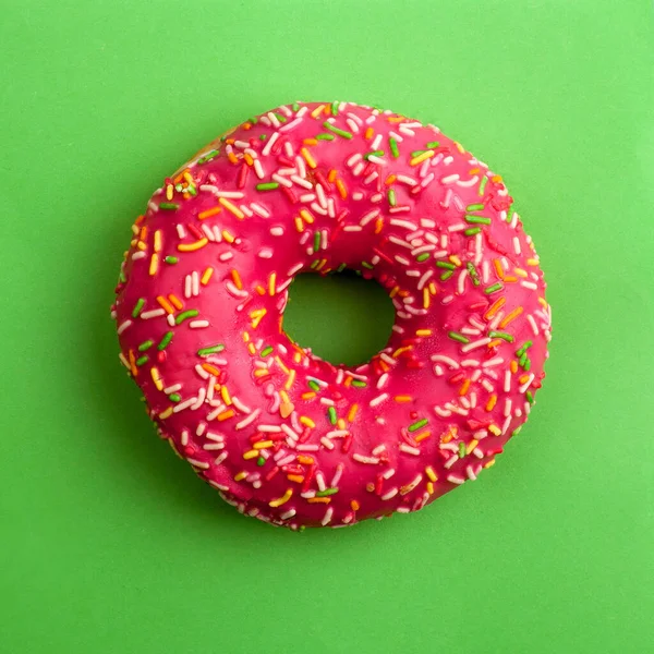 Yeşil arkaplanda pembe donut. Bir karenin üst görüntüsü.