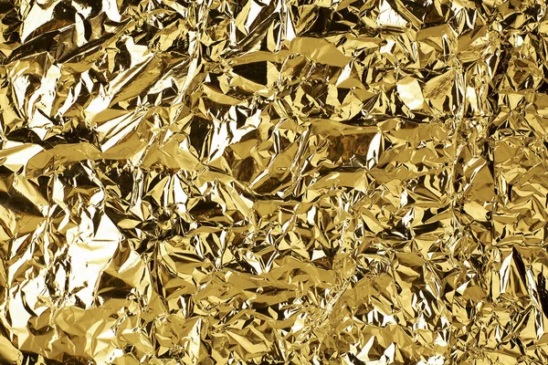 Crumpled golden foil shining texture background, bright shiny gold luxury design, metallic glitter surface, holiday decoration backdrop concept, gold metal shimmer effect, sparkling yellow pattern