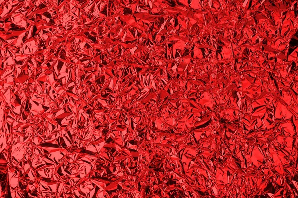 Crumpled red foil shining texture background, bright shiny festive design, metallic glitter surface, holiday decoration backdrop concept, metal shimmer light effect, sparkling red color pattern
