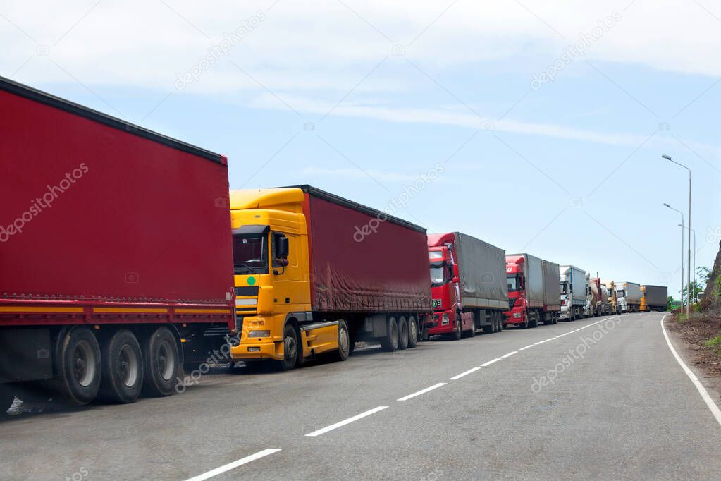 Queue of trucks passing the international border, red and different colors trucks in traffic jam on the road