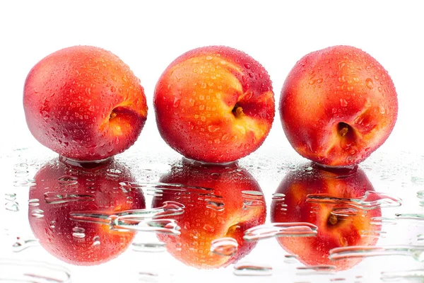 三颗桃子在白色的镜面上 与水滴隔离 闭合在一起 — 图库照片