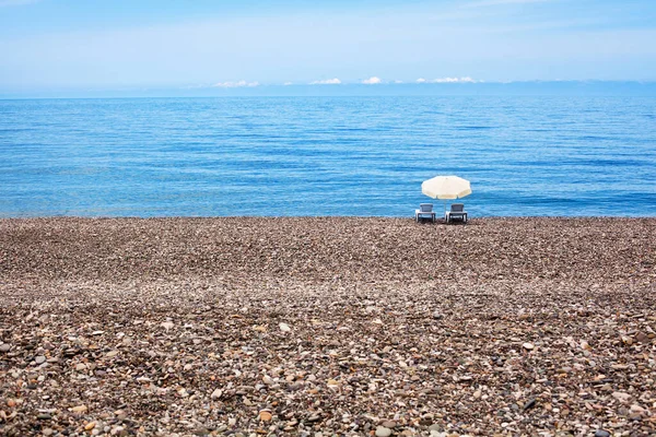 Два Пустых Шезлонга Белый Зонтик Солнца Прекрасном Одиноком Галечном Пляже — стоковое фото