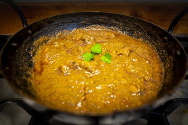 Geleneksel bir tavada kişniş ile süslenmiş köri.