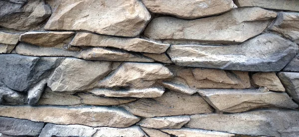 Parede de tijolo moderno é perto, feito de tijolos afiados desiguais de cores diferentes — Fotografia de Stock