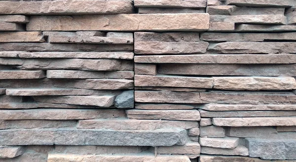 A textura é perto da parede que consiste em tijolos de pedras de cores diferentes e tons castanhos — Fotografia de Stock