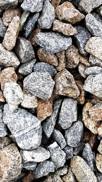 Macro photo of crushed stone and gravel on the ground. Texture background white gray stones on a black earth background.