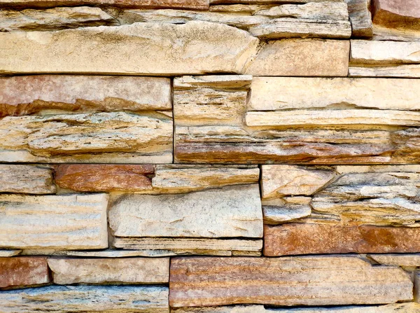 The texture of the wall is made of uneven stones of different sizes of sand and light brown color.. stone background. — стоковое фото