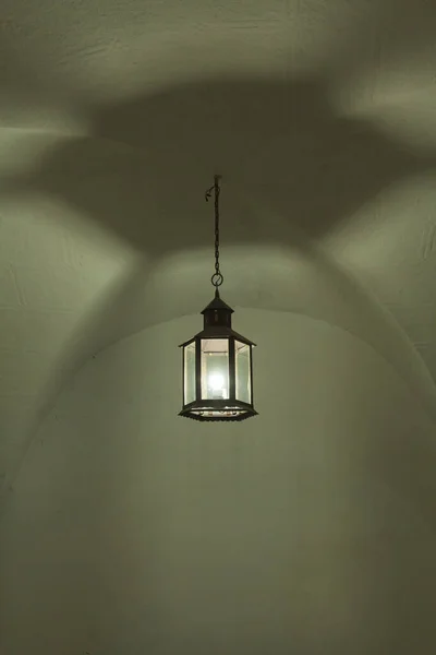 An artisan lamp hangs from an old vault in a medieval building in the city of Caceres.