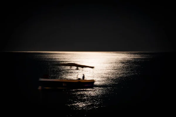 Ay ışığında deniz manzarası ve tekneler