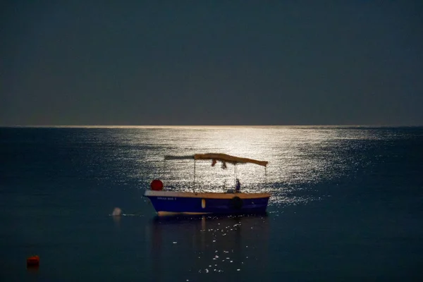 Ay ışığında deniz manzarası ve tekneler