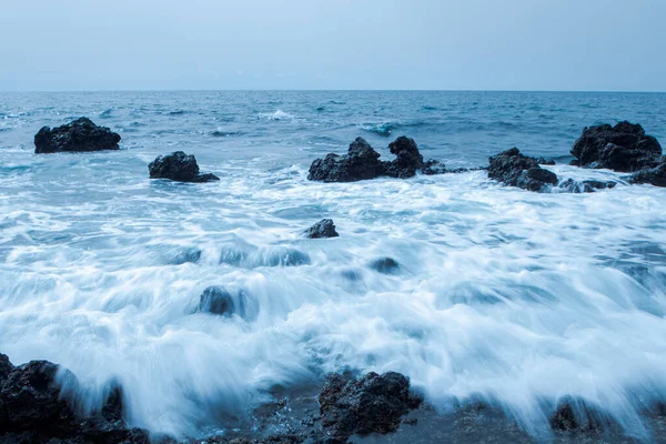 Deniz dalgaları kayalara su sıçratıyor..