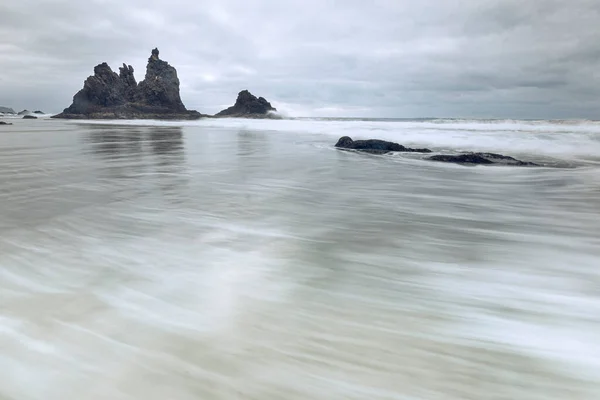 Ön planda hareket eden su, arka planda bulutlu kaya ve simge.