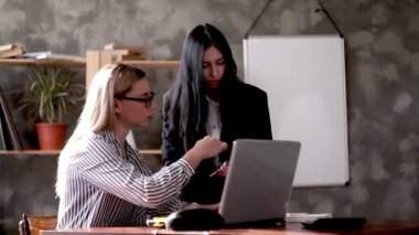 Ofiste iki kız dijital tablet kullanarak bilgisayardaki verileri kontrol ediyor. Şirket çalışanları başkanın görevlerini tartışır